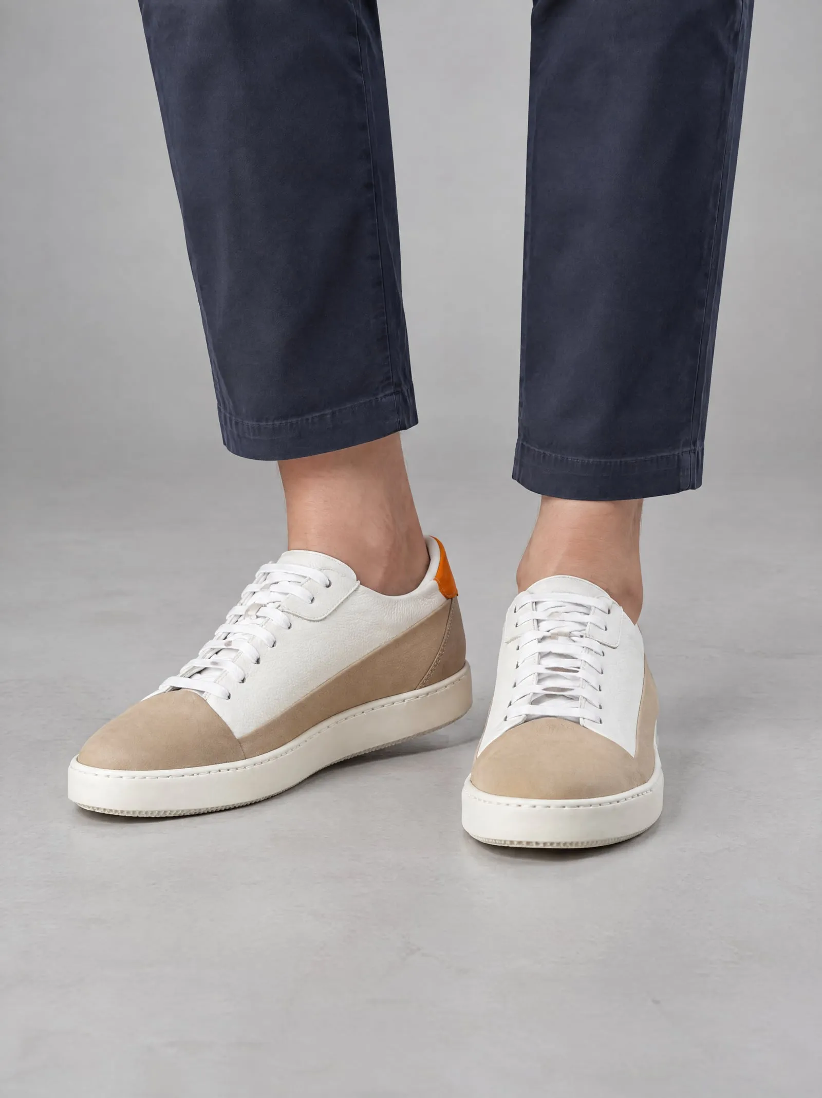 Iris wearing the sand suede court sneakers, close up, in a grey studio