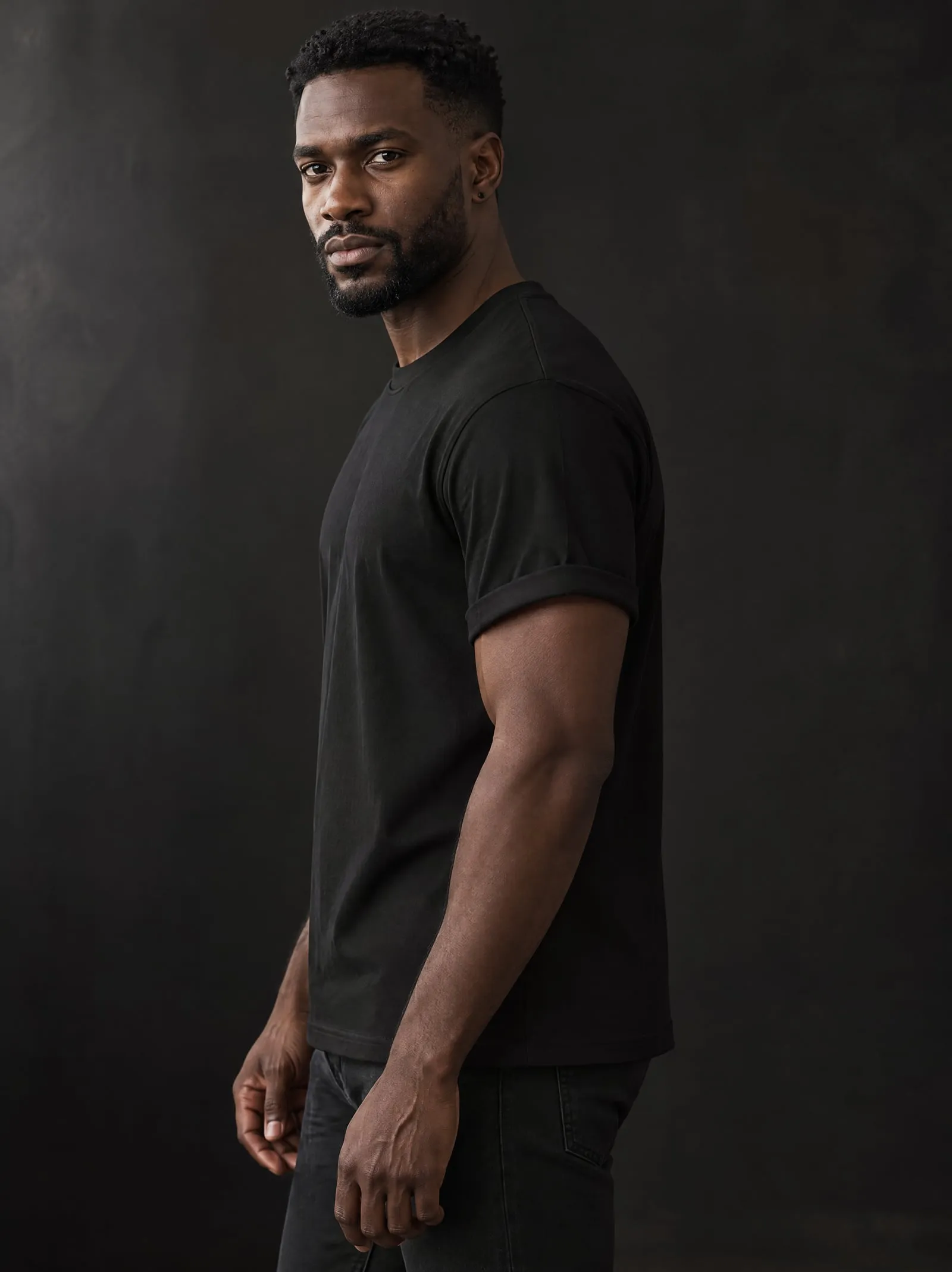 Malik wearing the black T-shirt, in profile, in a dark studio