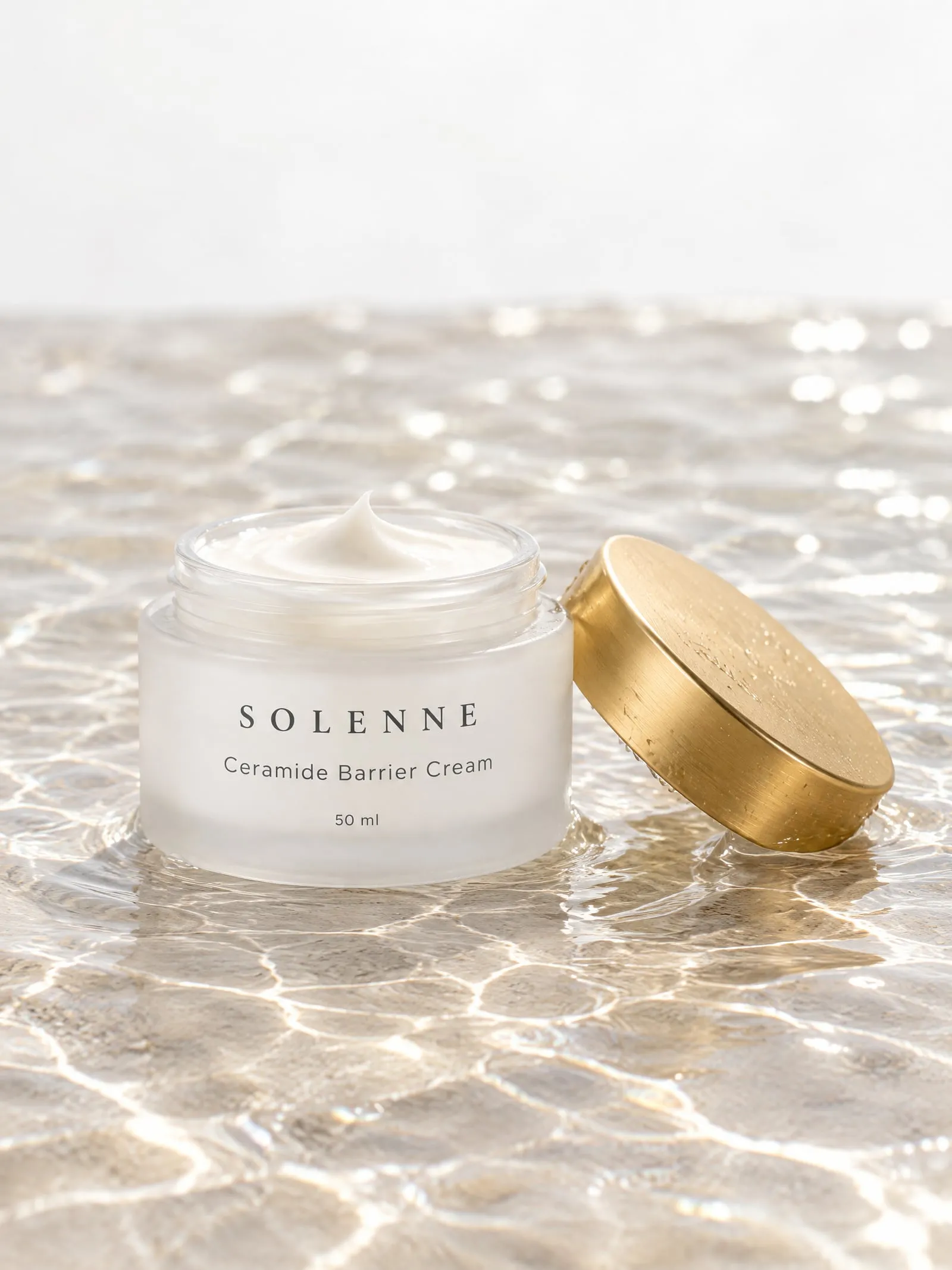 The SOLENNE ceramide cream, lid off beside, in shallow water
