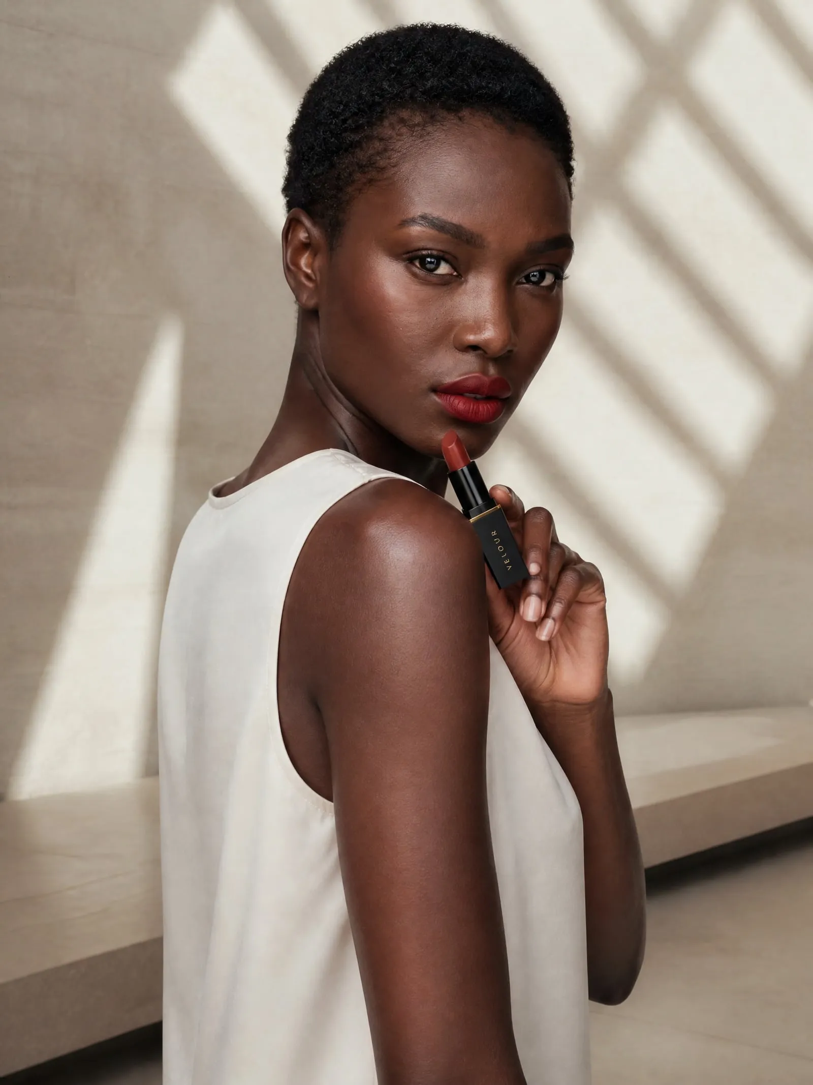 Amara with the VELOUR satin lipstick, glance over shoulder, in window light and shadow